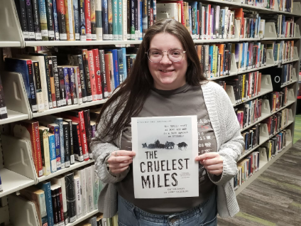 Abbi holding her Recommendation "The Cruelest Miles"